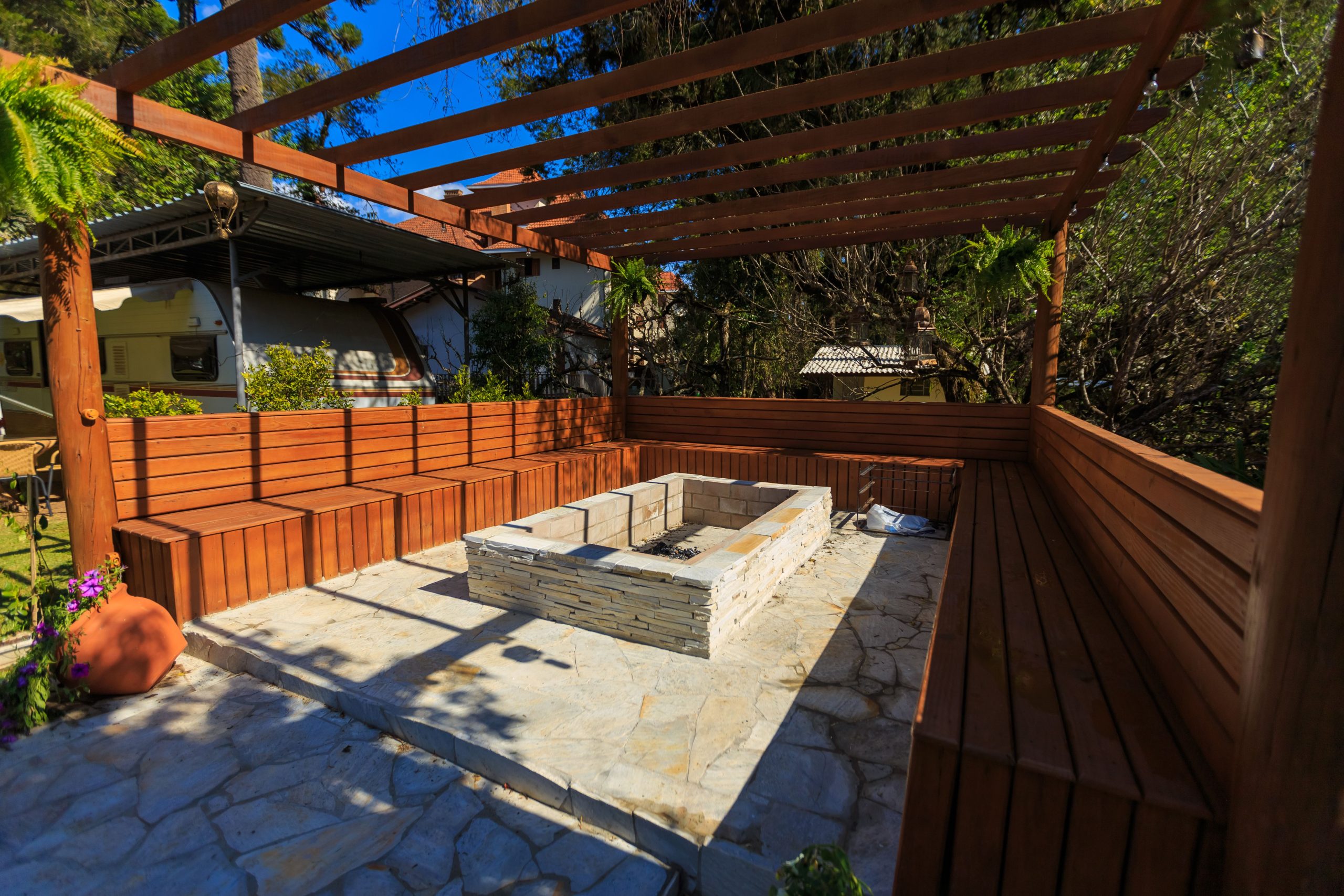 Pergola avec foyer en pierre et bancs bois confortables.