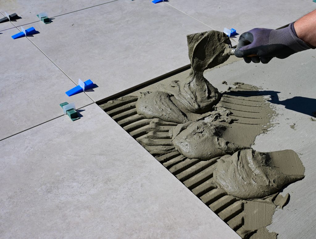 Main gantée appliquant joint carrelage flexigrout