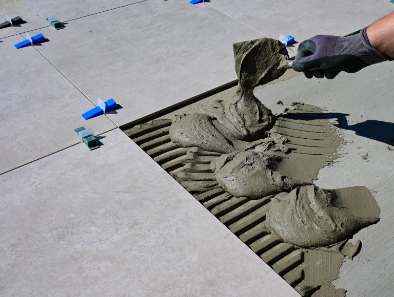 Main gantée appliquant joint carrelage flexigrout