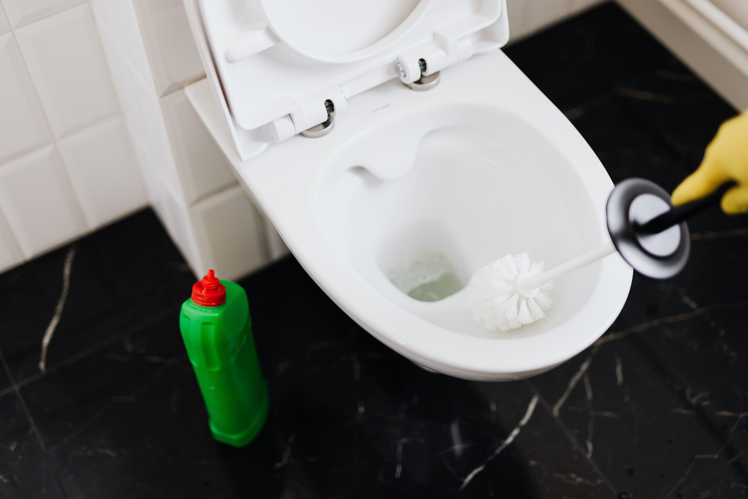 Personne nettoyant toilette avec brosse et gants