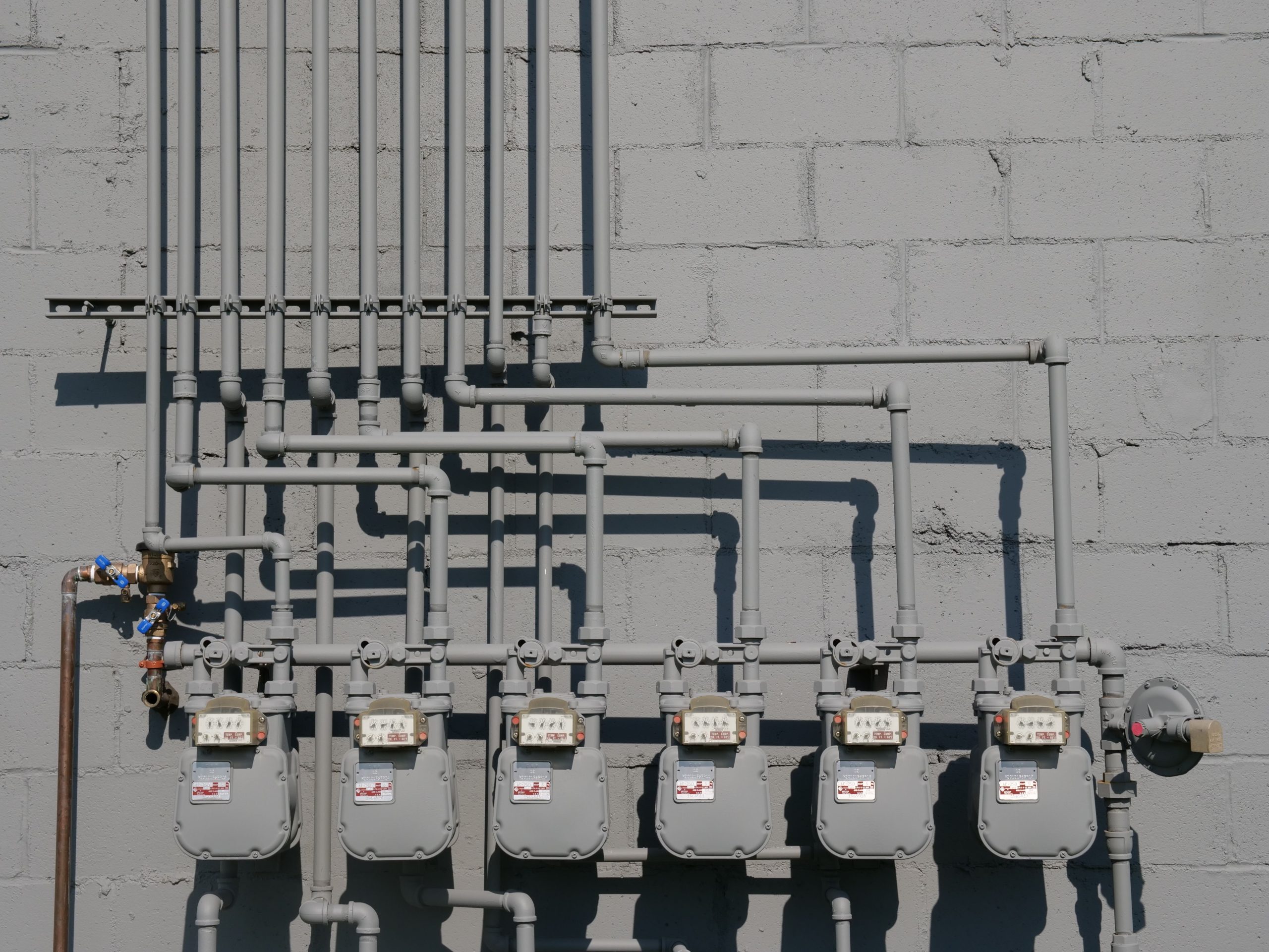 Rangee compteurs gaz tuyauterie mur beton