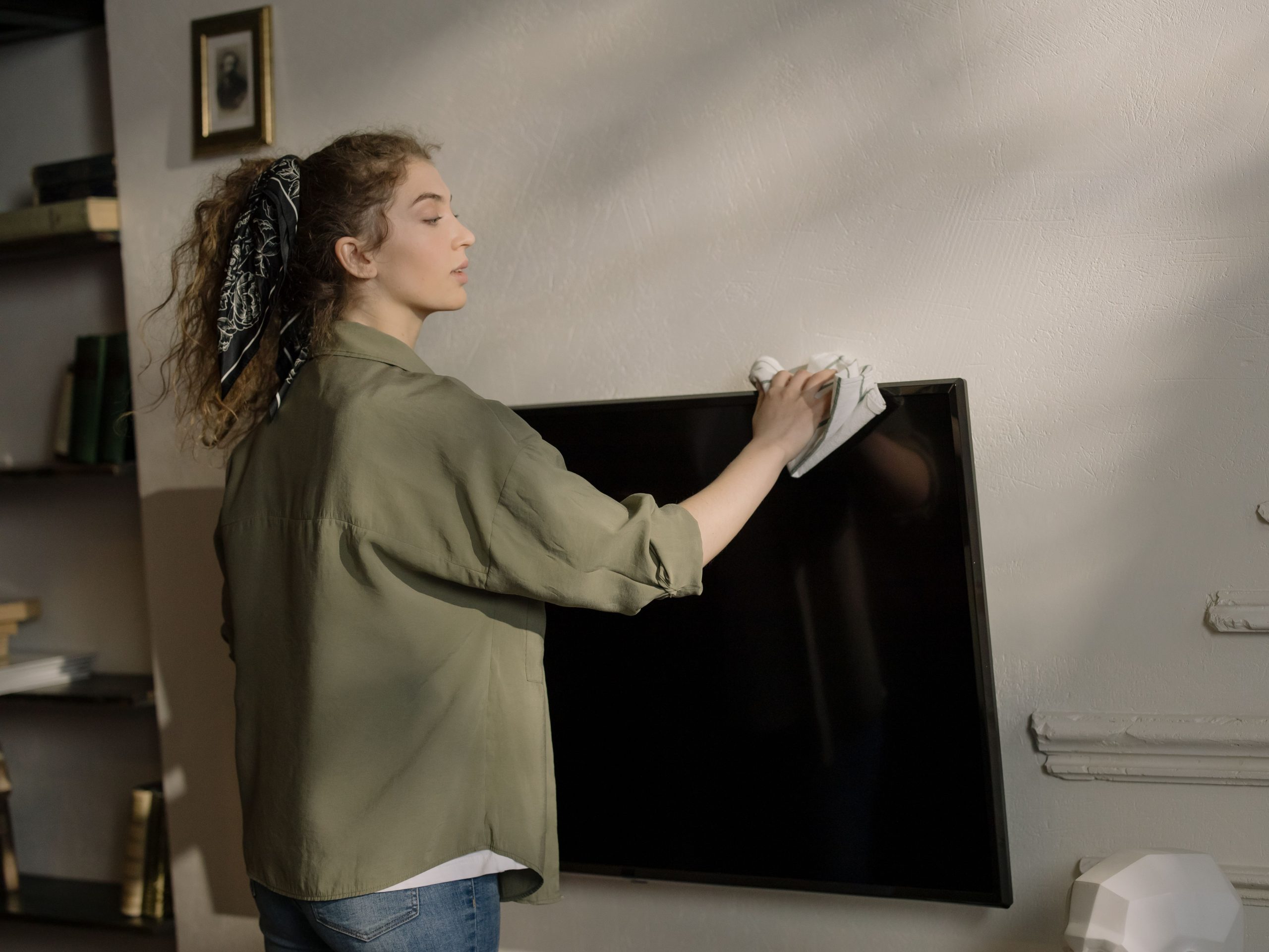 Femme cheveux bouclés nettoie écran télévision