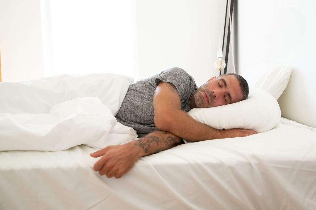 Homme dormant paisiblement sur un lit blanc