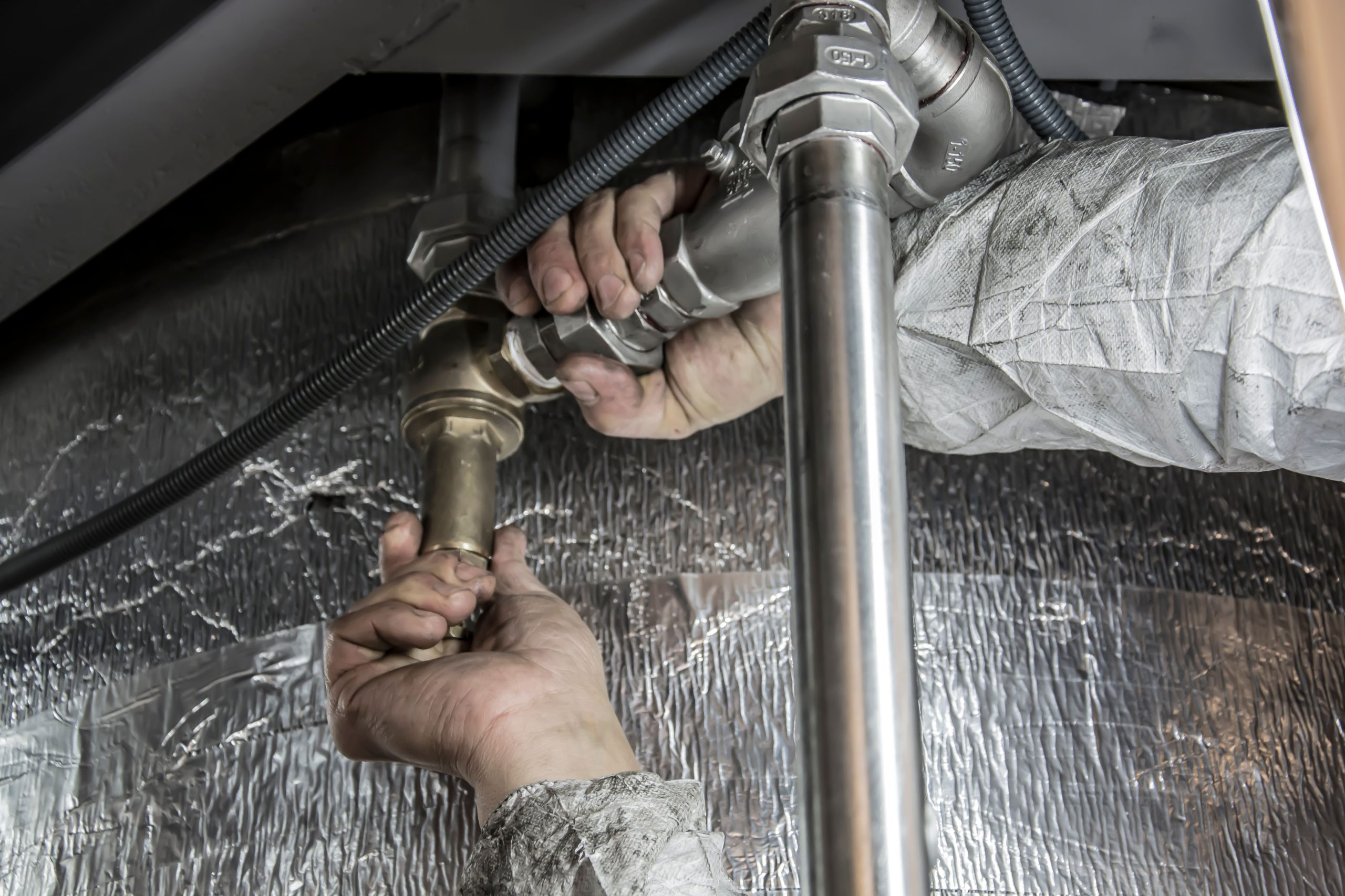 Plombier installant tuyauterie acier avec outils spécialisés