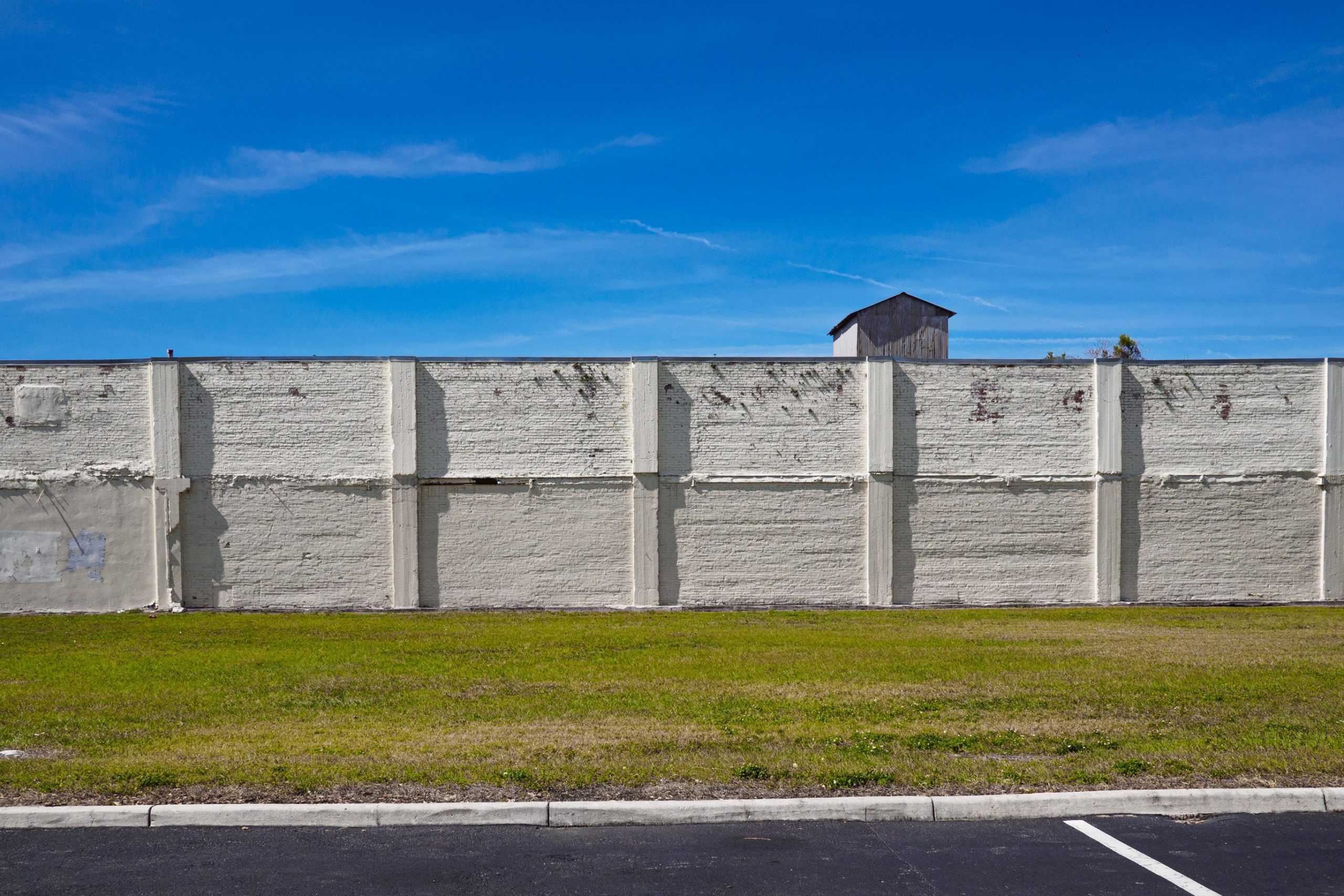 Mur beton gris sous ciel bleu et herbe