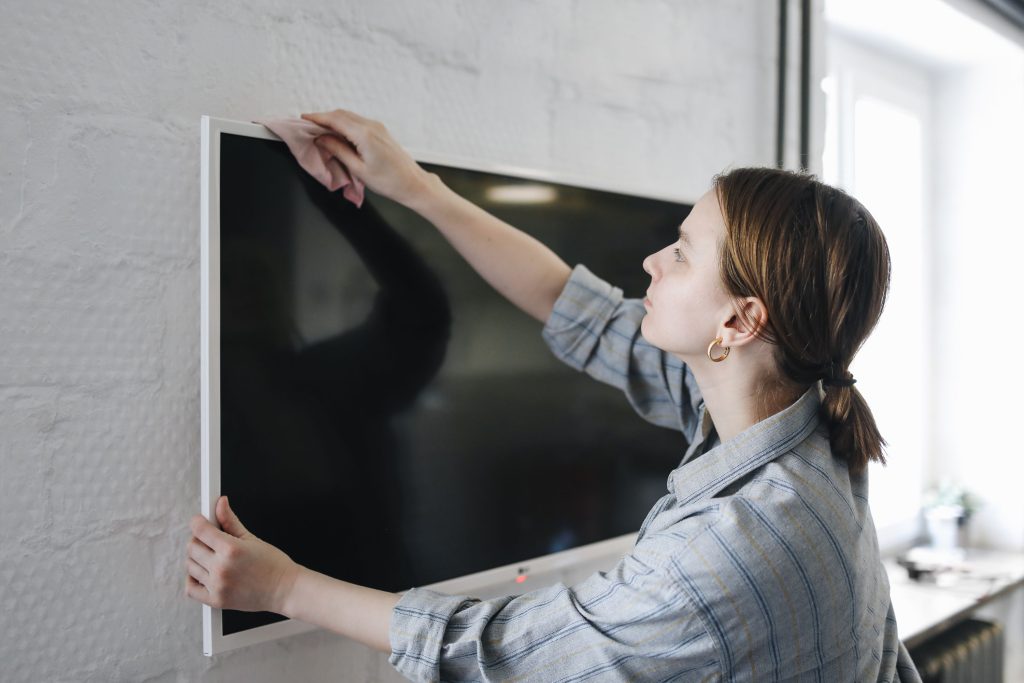 Femme nettoie écran télé plat intérieur