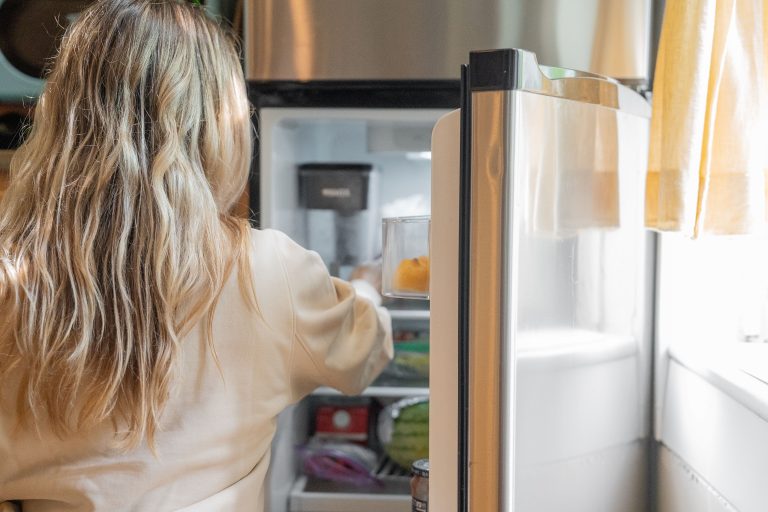 Femme blonde sortant aliments du refrigerateur cuisine