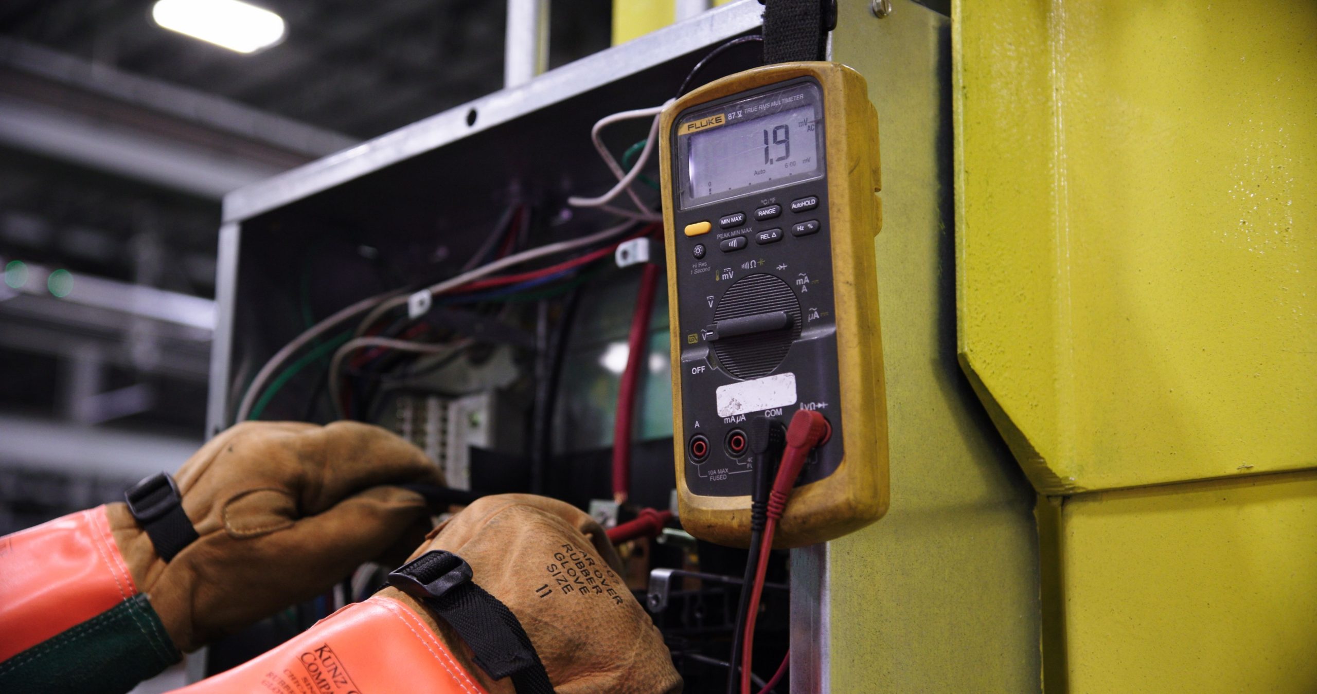 Électricien utilisant multimètre sur panneau de contrôle